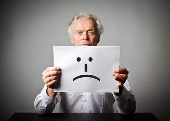 Old man in white is holding white paper with smile. Unhappy concept.