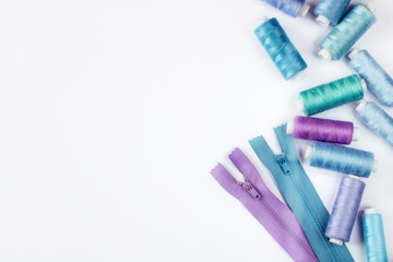 Sewing supplies and accessories for needlework. Spools of thread and other equipment blue violet colour that uses a tailor to sew clothes on white background.