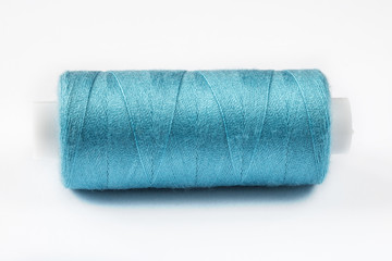 A blue thread reel for sewing clothes close-up on a white background