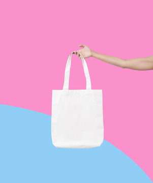 hand holding bag canvas fabric for mockup blank template isolated on color background.