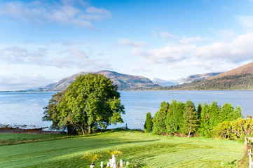 Landscape with beautiful scottish wild mountains lake and green garden