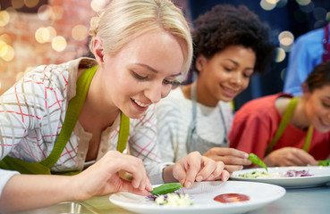 happy women cooking and decorating dishes