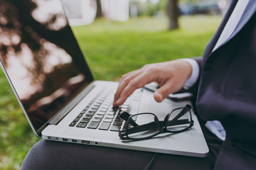 Close up cropped of hands on the keyboard. Businessman in classic suit, glasses. Man sit on soft...