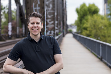 Fototapeta premium Portrait of a Handsome Man Posing on a City Bridge