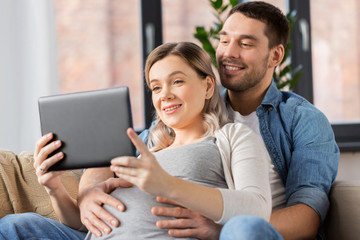 man and pregnant woman with tablet pc at home