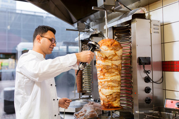chef slicing doner meat from spit at kebab shop