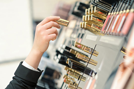 A woman takes a lipstick, in a cosmetics store