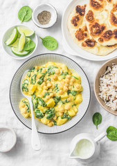 Vegetarian chickpea, spinach, potato curry, wild rice and naan flatbread on white background, top view. Indian healthy food concept