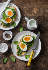Delicious healthy breakfast - grilled bread sandwich with spinach and boiled eggs on wooden background, top view