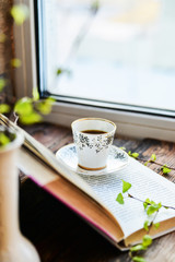 open book, coffee mug by the window, the concept of dreams and thoughtfulness