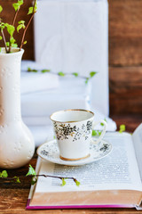 open book, coffee mug, branches with green leaves, the concept of love for reading, spring and freshness