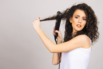beautiful hair model girl young adult with curly hair and hair iron straightener happy and unhappy concept 