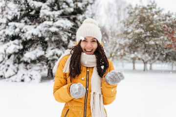 Laughing woman playing with snow while walking in park