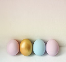 A row of pastel colored Easter eggs on white background. Festive easter background in minimalism style.