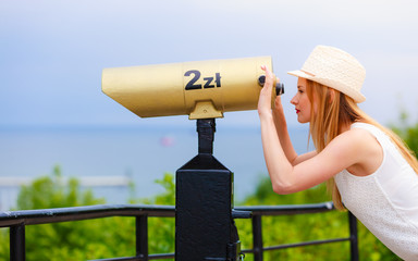 Woman tourist with sun hat looking through telescope