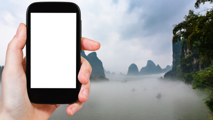 tourist photograps fog over river in Yangshuo