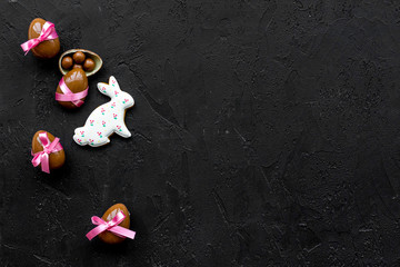 Easter candy. Traditional Easter signs and symbols. Chocolate Easter eggs and Easter bunny cookies. Black background top view copy space