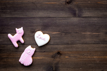 Valentine's Day candy. Heart shaped cookie with lettering Love and kitty on dark wooden background top view space for text