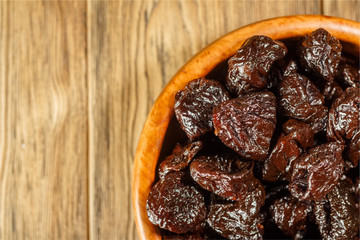 Prunes in a bowl made of beech. Place for text. Dietary food.