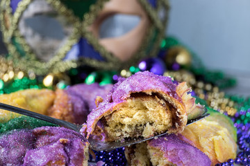 Mardi Gras celebration with king cake slice, hanging beads, and mask