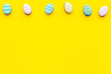 Easter gingerbread and cookies in shape of Easter eggs. Yellow background top view copy space