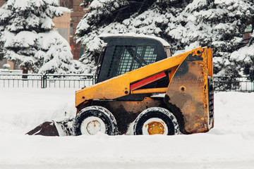 the snowplow stands on the street during the day