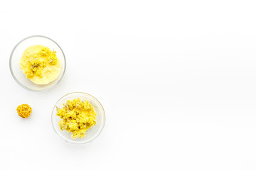 Aromatic spa salt. Yellow spa salt with delicate spring flowers on white background top view copy space