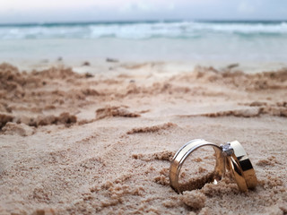 Wedding rings on white sand on an ocean background