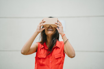 A young Indian Asian woman tries VR (Virtual Reality) goggles for the first time and is surprised and delighted. She is smiling and laughing whilst looking up.