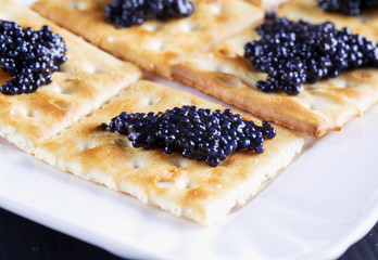 Black caviar over crackers, white tray