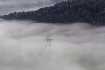 Hochspannungsleitung im Nebel im Tal