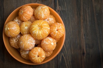 Bowl purified sweet mandarins on dark wooden background