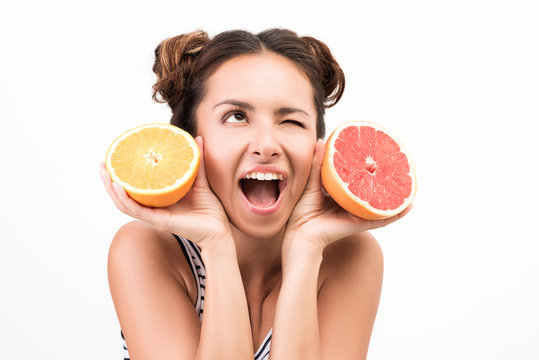 Young cheerful woman holding fruit. Orange and grapefruit. Joy and good mood