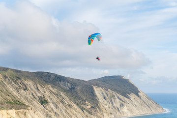 Fototapeta na wymiar Flying tandem paragliders over the sea and near the mountains, beautiful landscape view
