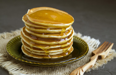 Pancakes with honey on a gray background.