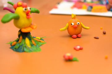 Rooster and chicken from plasticine on a yellow background.