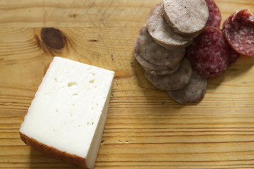 Cheese and sausages cut on a cutting board. Horizontal shot