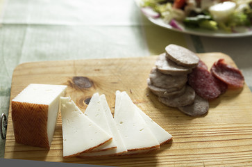 Fototapeta na wymiar Cheese and sausages cut on a cutting board. Horizontal shot