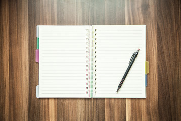 Pen and notepad on a wood background.