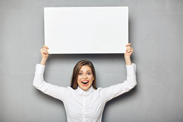 Smiling business woman holding raised up empty white sign board.