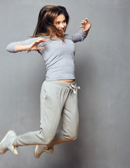 Happy woman casual dressed jumping on gray wall background.