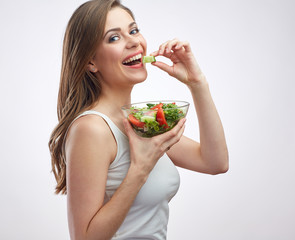 Happy young woman eating salad with cucumber.