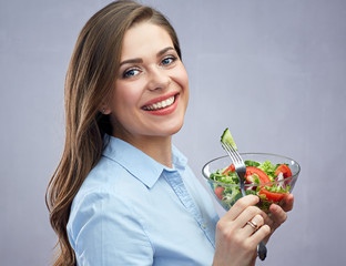 Smiling young woman holding glass salad bowl and fork.