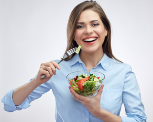 Smiling woman eating salad from glass bowl.