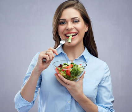 Happy smiling woman eating osalad with fork.
