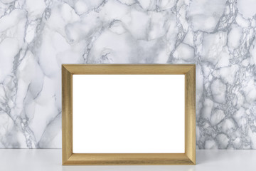 White desk, marble gray wall and gold horizontal empty frame
