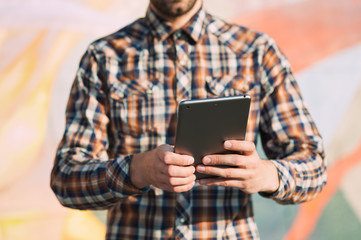 Unrecognizable casual businessman using a modern digital tablet downtown on the street
