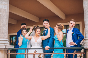 Full length portrait of newlywed couple and their friends at the wedding party.  Bridesmaids and groomsman with Bride and groom near columns 