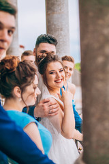 Full length portrait of newlywed couple and their friends at the wedding party.  Bridesmaids and groomsman with Bride and groom near columns 