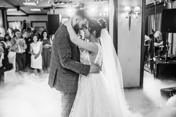 Naklejka premium First dance the bride and groom in the smoke. brides wedding party in the elegant restaurant with a wonderful light and atmosphere